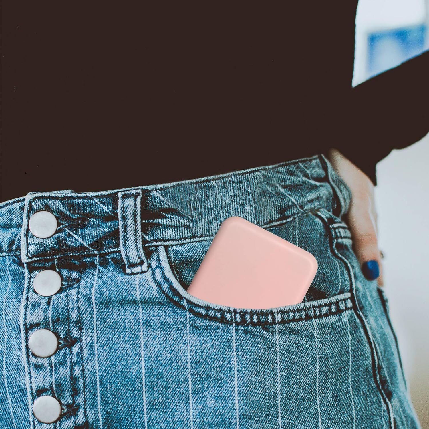 Person wearing denim jeans with a pink portable charger visible in the pocket.